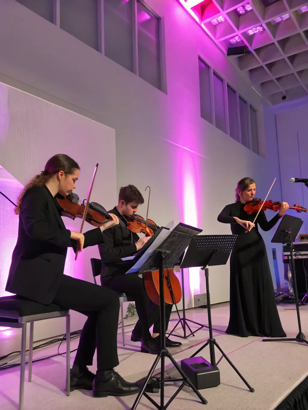 A vibrant image of a string quartet performing on a brightly lit stage, capturing the energy and passion of a live musical performance, to promote an upcoming classical music concert.